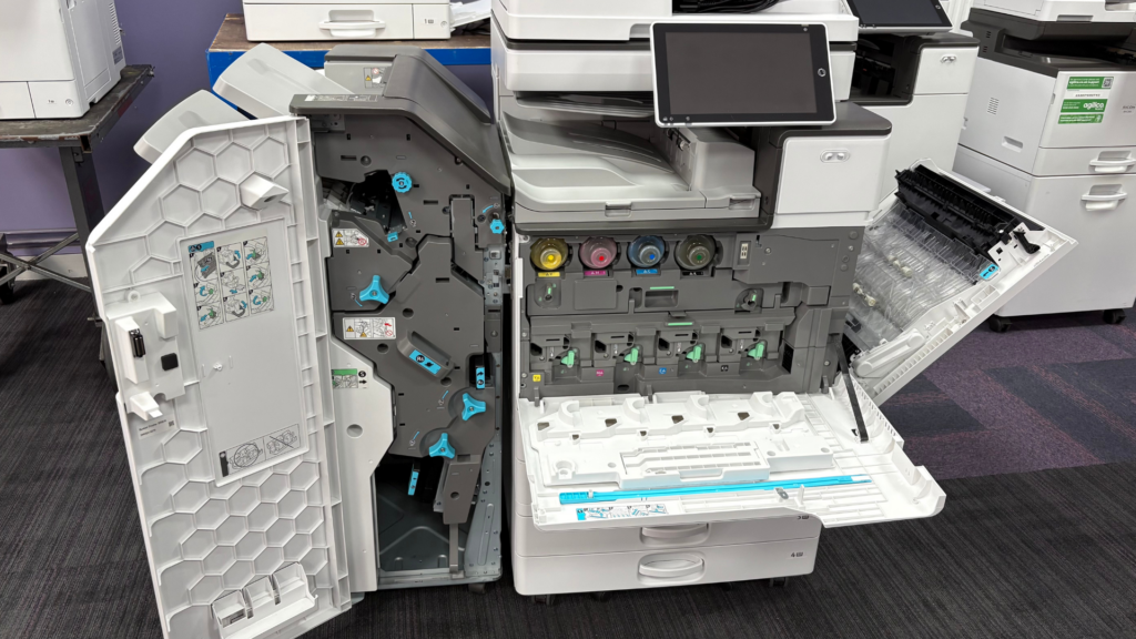 Open multifunction printer showing internal toner cartridges and service components during maintenance or refurbishment.
