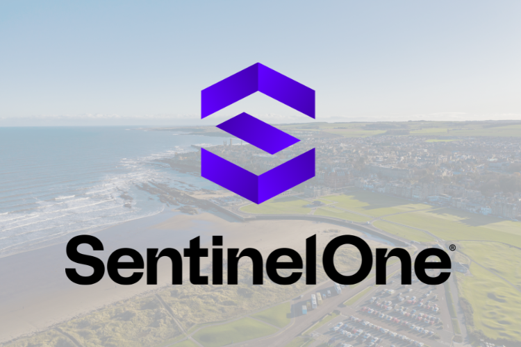 SentinelOne logo displayed prominently over a faded aerial photograph of a coastal town and shoreline. The logo consists of a purple geometric emblem above the black text “SentinelOne,” centered on the image. The background shows a beach, ocean waves, green open spaces, roads, and buildings viewed from above, with a light grey overlay that softens the scene.